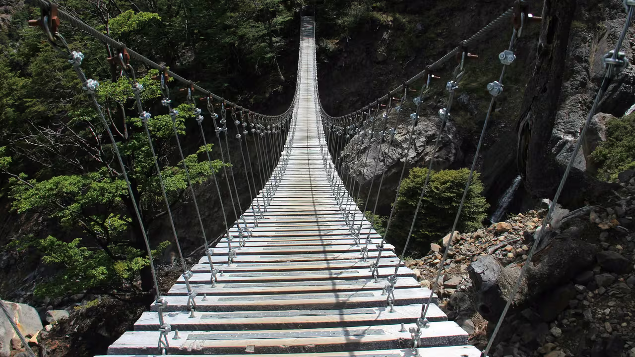 Wooden suspension footbridge stretching across a rocky canyon